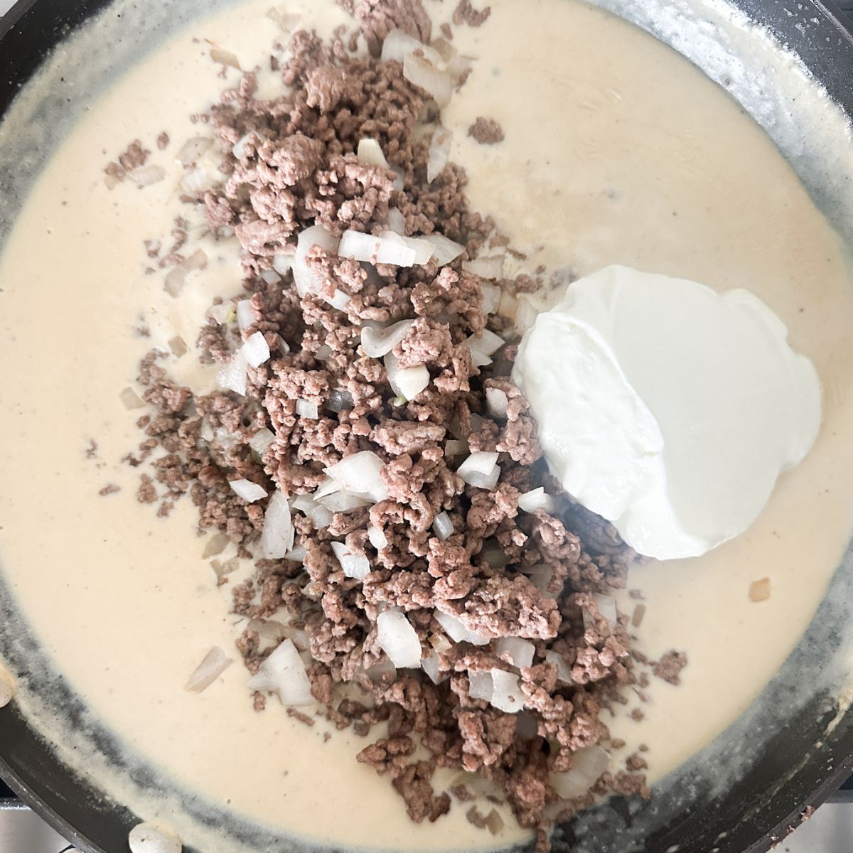 Skillet with creamy sauce, ground beef, and sour cream. 
