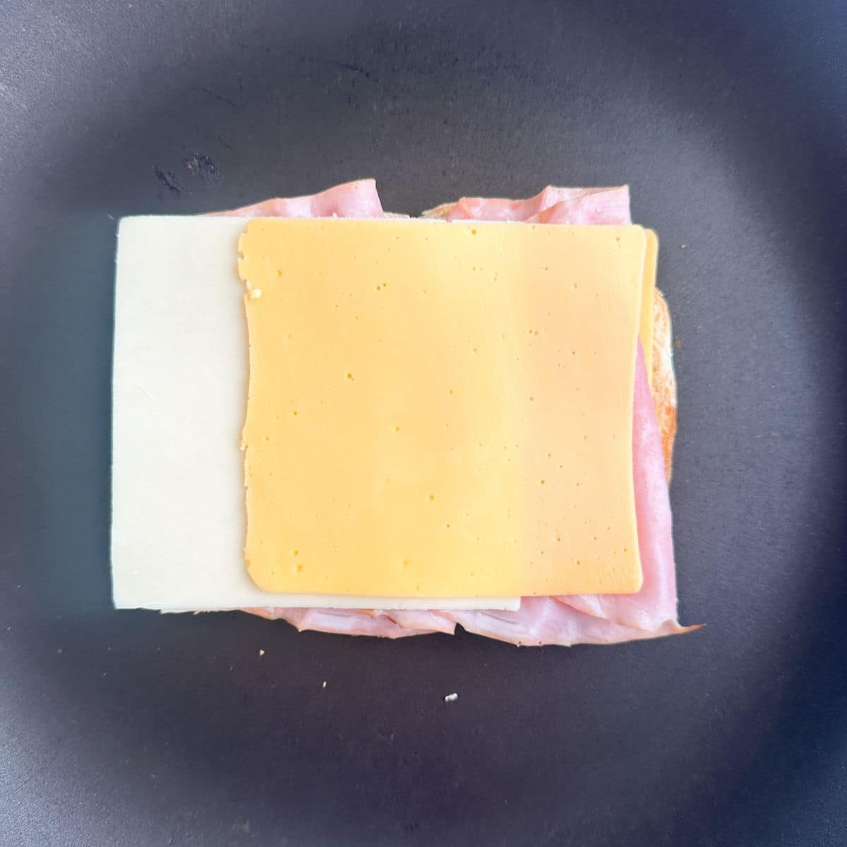 Sliced cheese on ham and bread. 