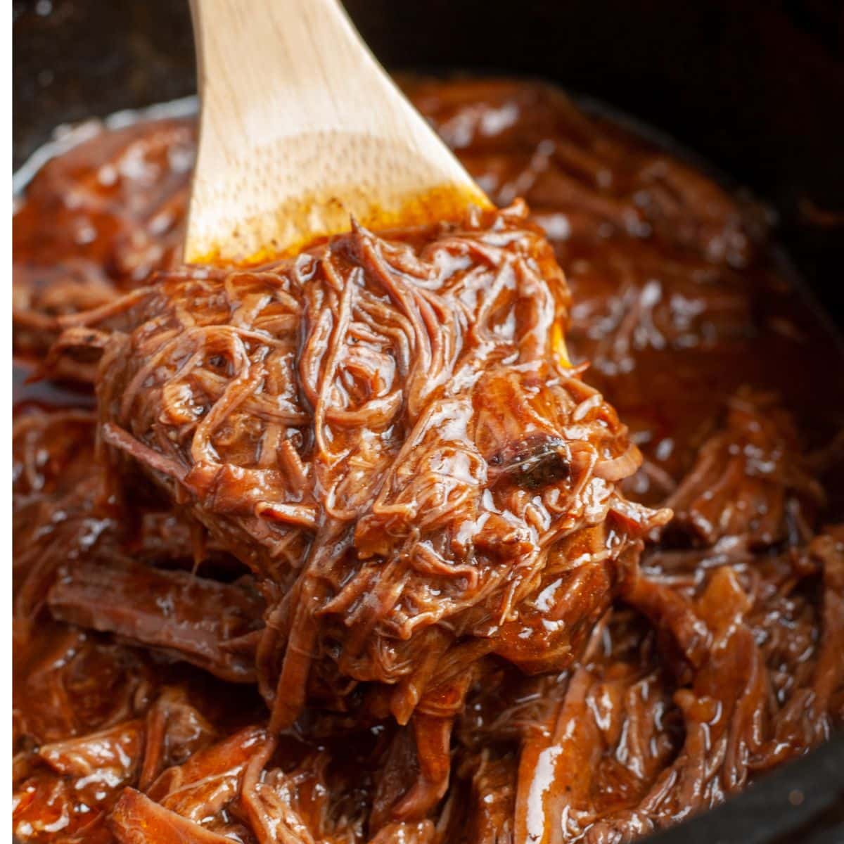 Wooden spoon holding bbq shredded beef. 
