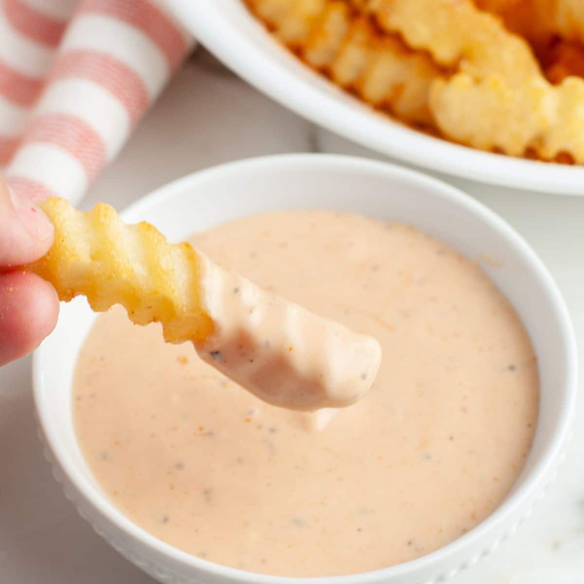 Bowl of fry sauce with a crinkle fry. 