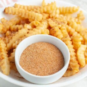 Bowl of seasoning with crinkled fries.