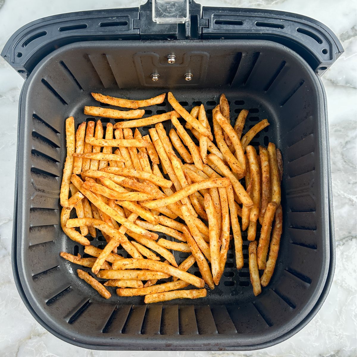 Cooked french fries in an air fryer basket. 