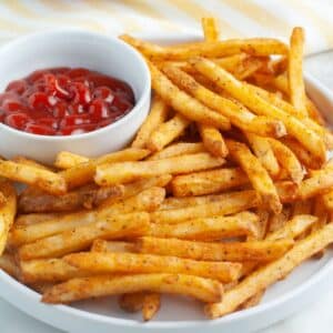 French fries on a plate with bowl of ketchup.