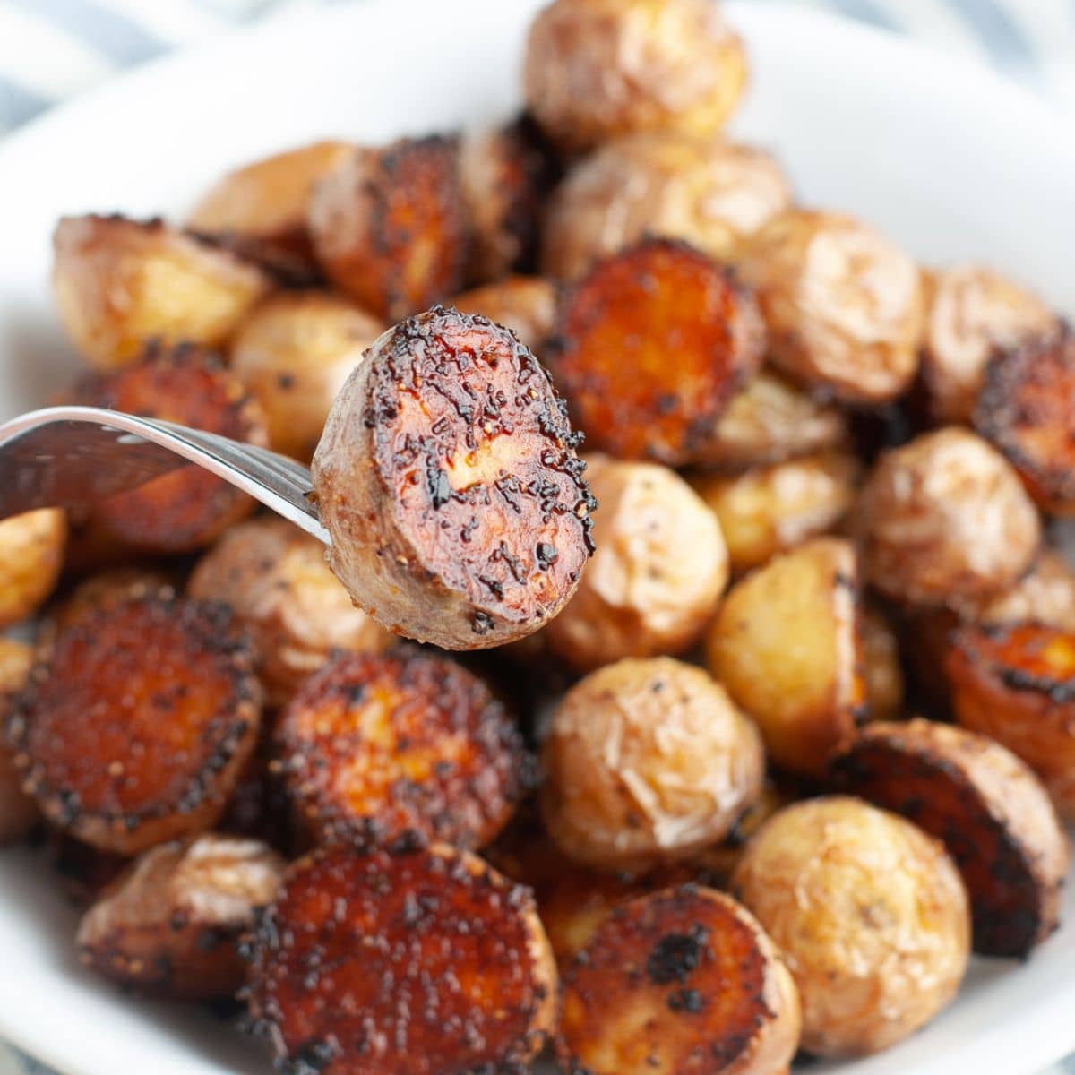 Fork holding a roasted potato.