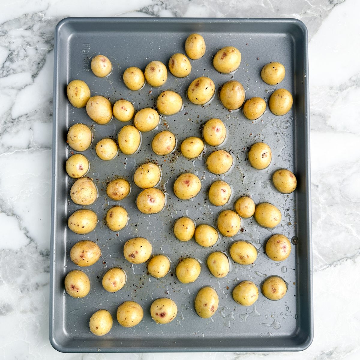 Small potatoes cut in half on a baking sheet. 