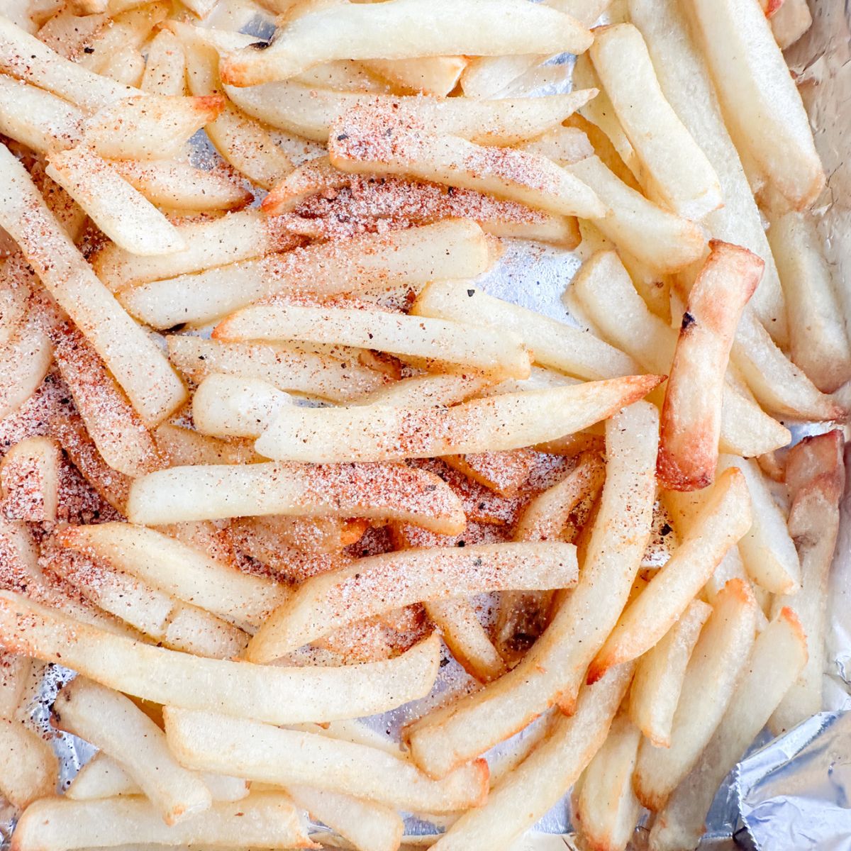 Seasoned fries on a foil lined tray.