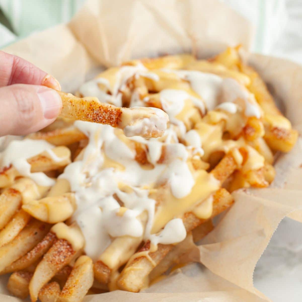 Hand holding Voodoo fries with cheese sauce. 