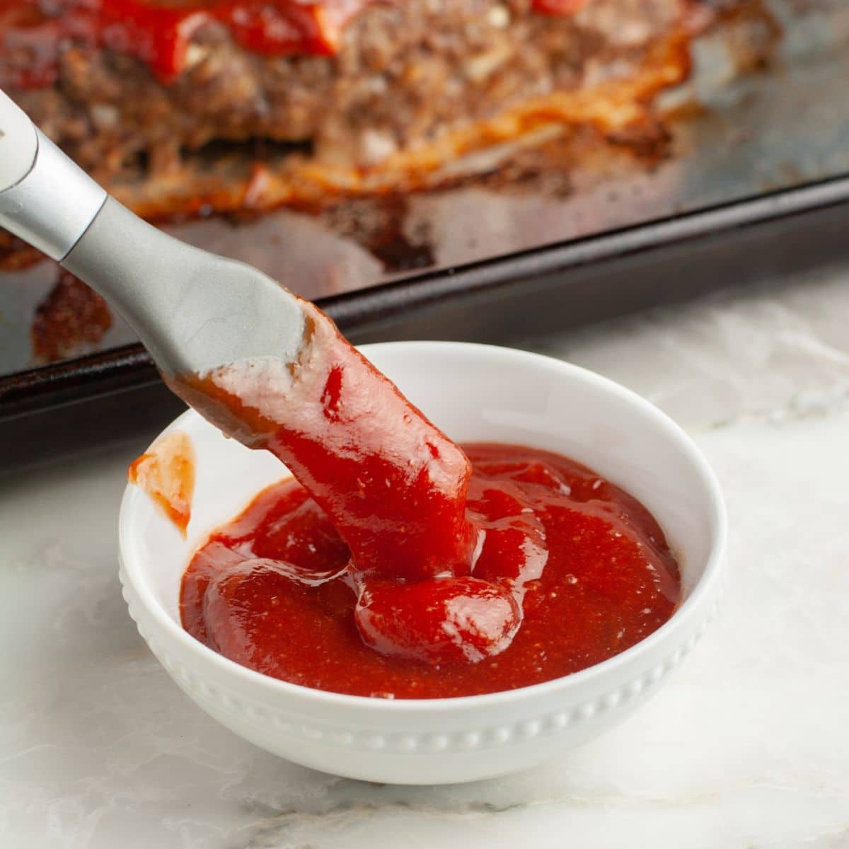 Bowl with ketchup and a brush. 