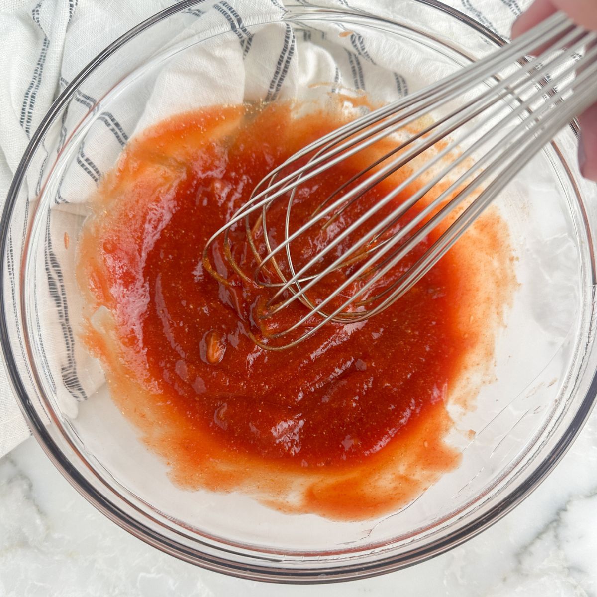 Bowl of meatloaf sauce with a whisk.