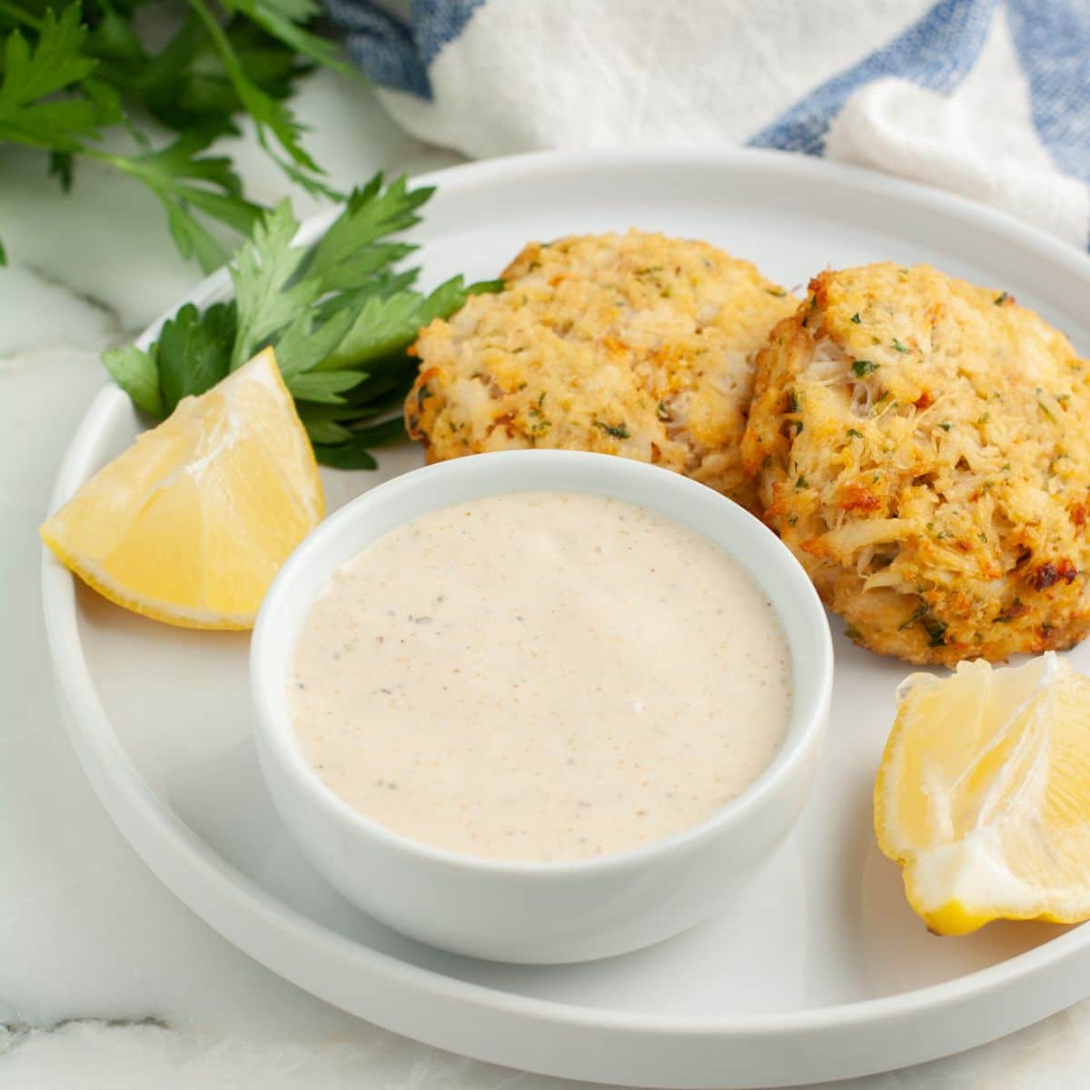 Bowl with Old Bay sauce and crab cakes. 