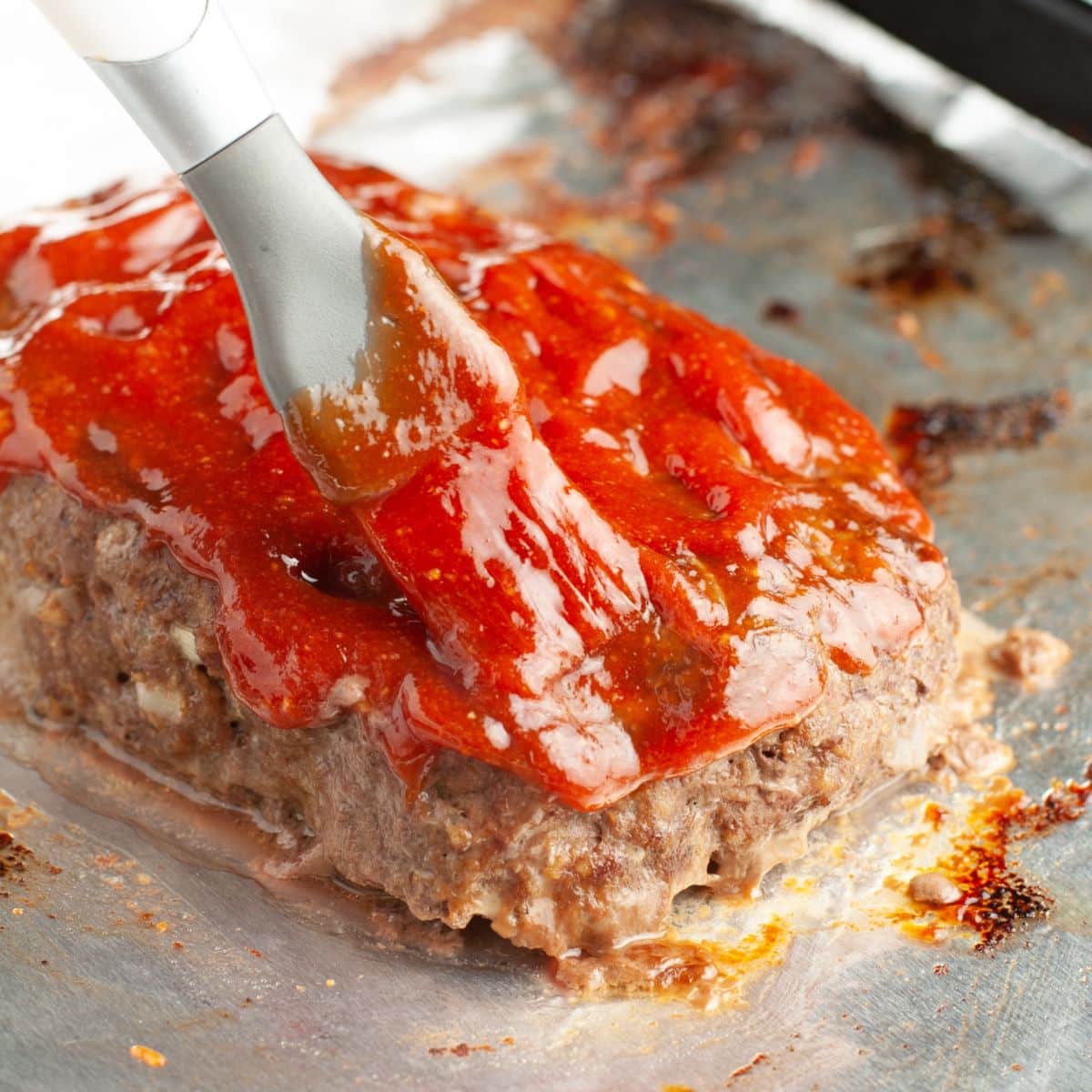 Brushing on meatloaf sauce on meatloaf.