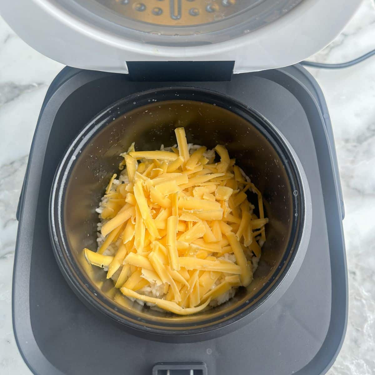 Rice and shredded cheese in rice cooker.