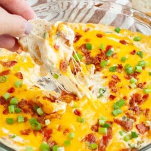 Hand holding bread with hot bacon dip.