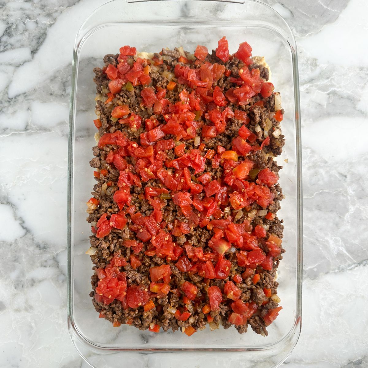 Casserole dish with ground beef and Rotel tomatoes.