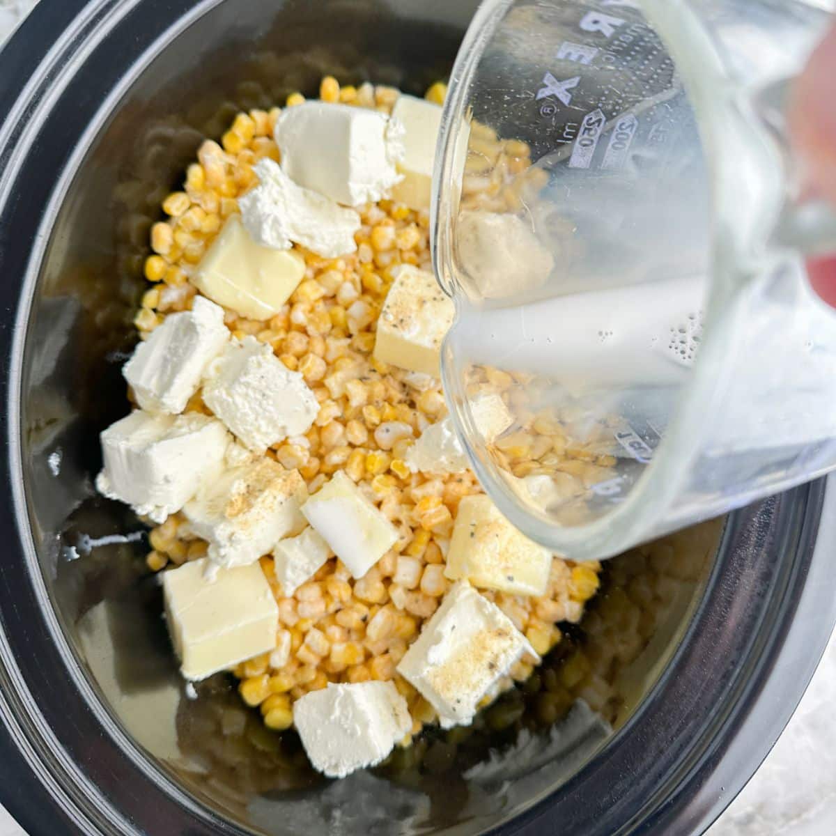 Slow cooker with corn, cream cheese, butter, and half and half.