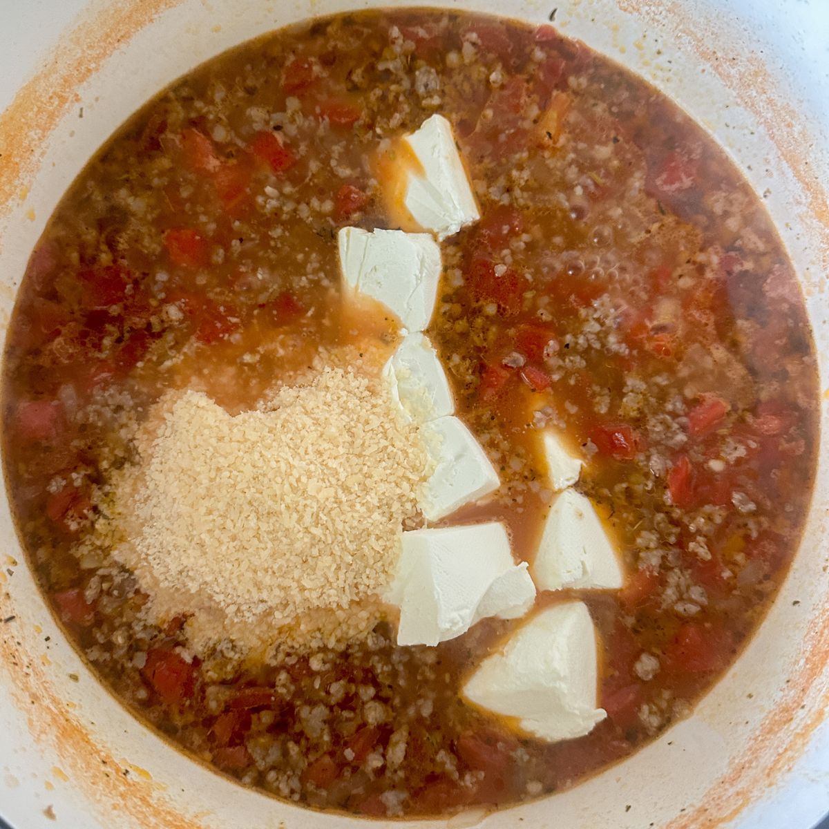 Pot with soup, cream cheese, and grated parmesan.