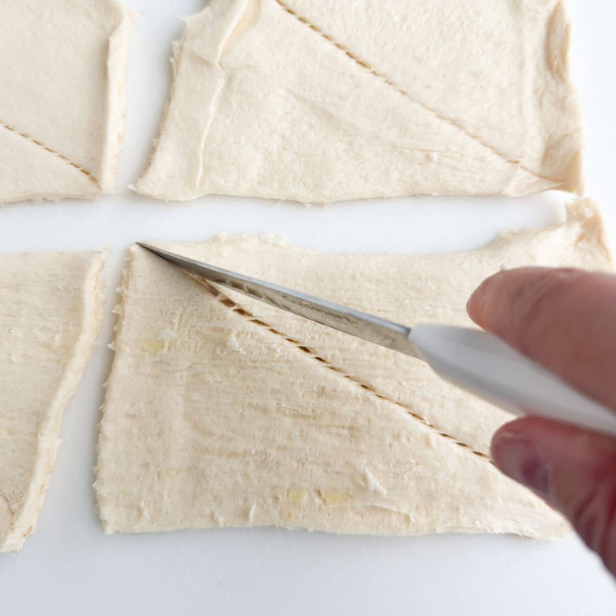 Cutting crescent roll dough.