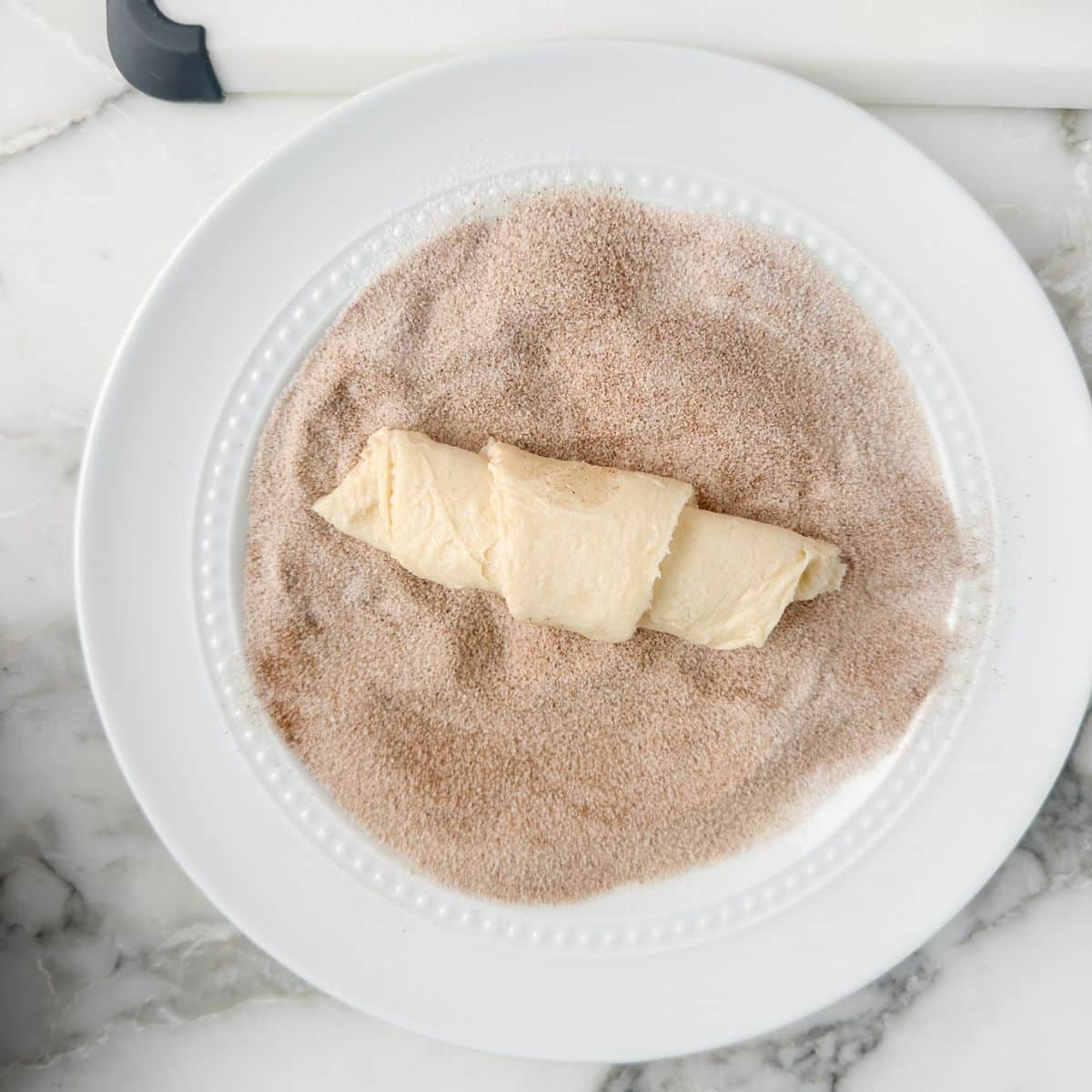 Plate of cinnamon sugar with a crescent roll.