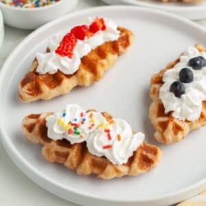 Three croffles on a plate topped with whipped cream.