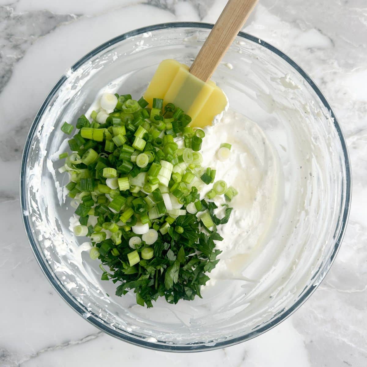 Bowl of mixed cream cheese, diced green onion, and fresh parsley. 