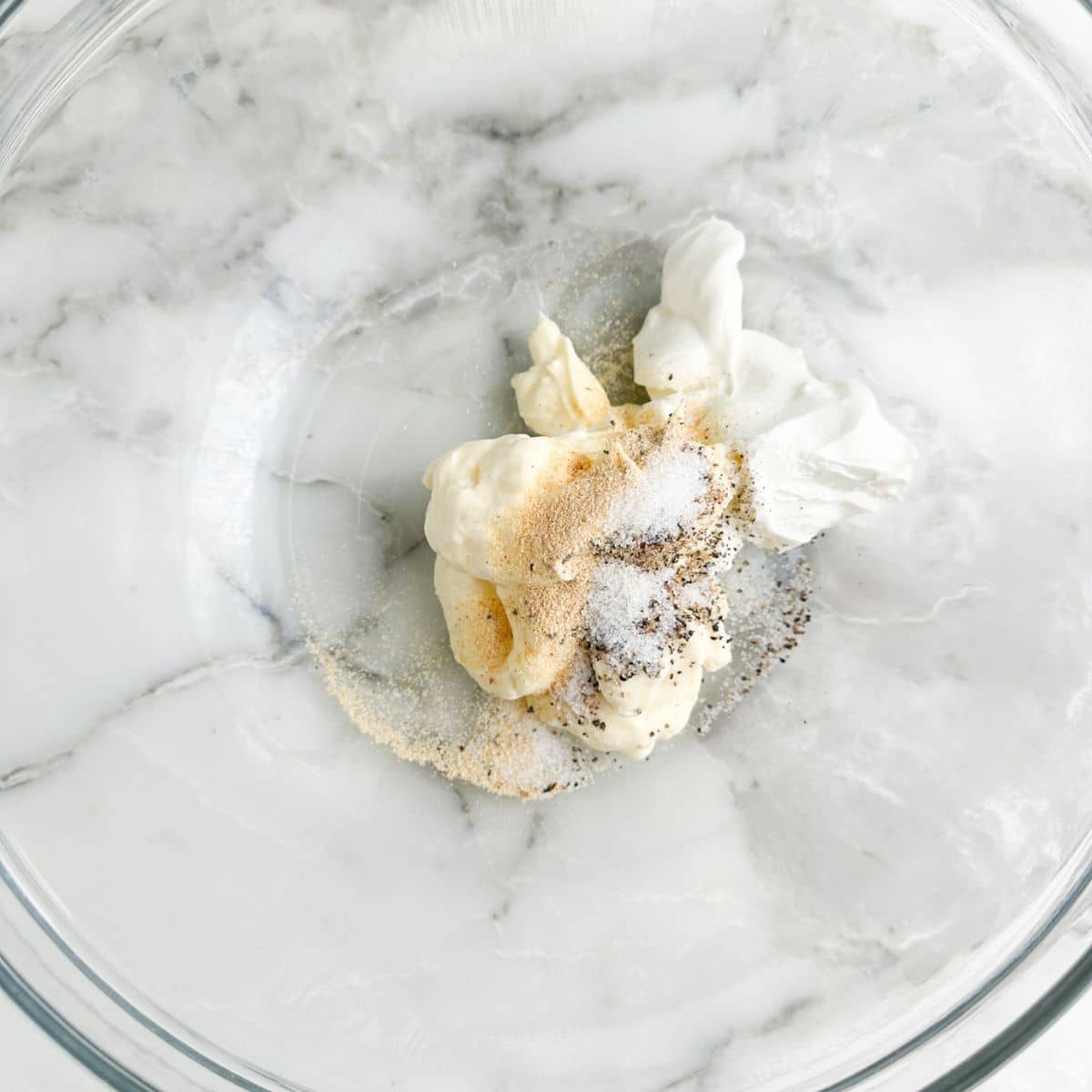 Bowl with mayonnaise, sour cream, and seasonings. 