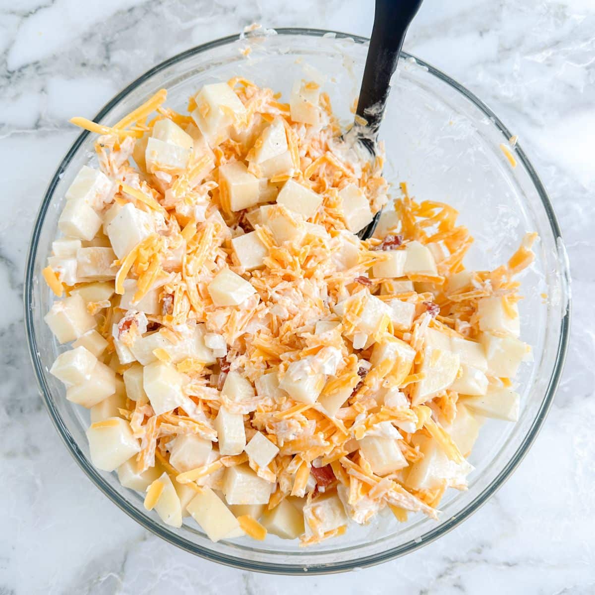 Bowl of diced potatoes and shredded cheese.