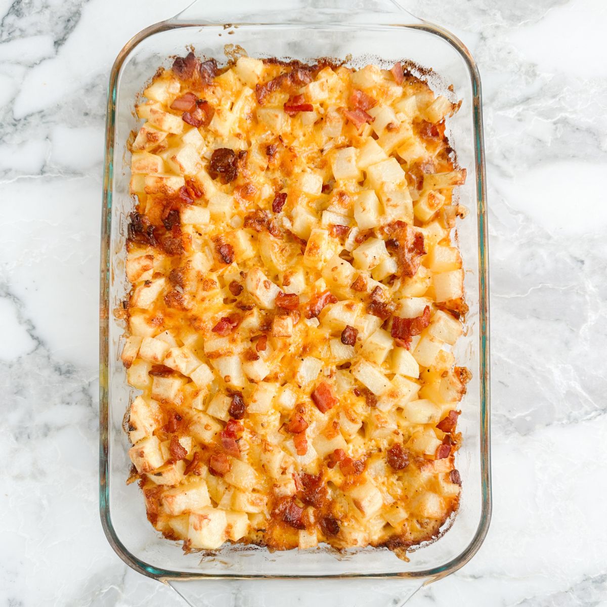 Baking dish with baked diced potatoes and bacon.