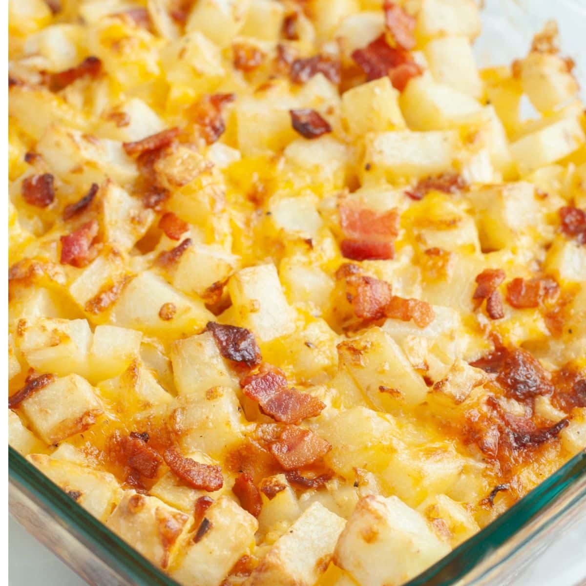 Casserole dish with baked diced potatoes, cheese, and bacon.