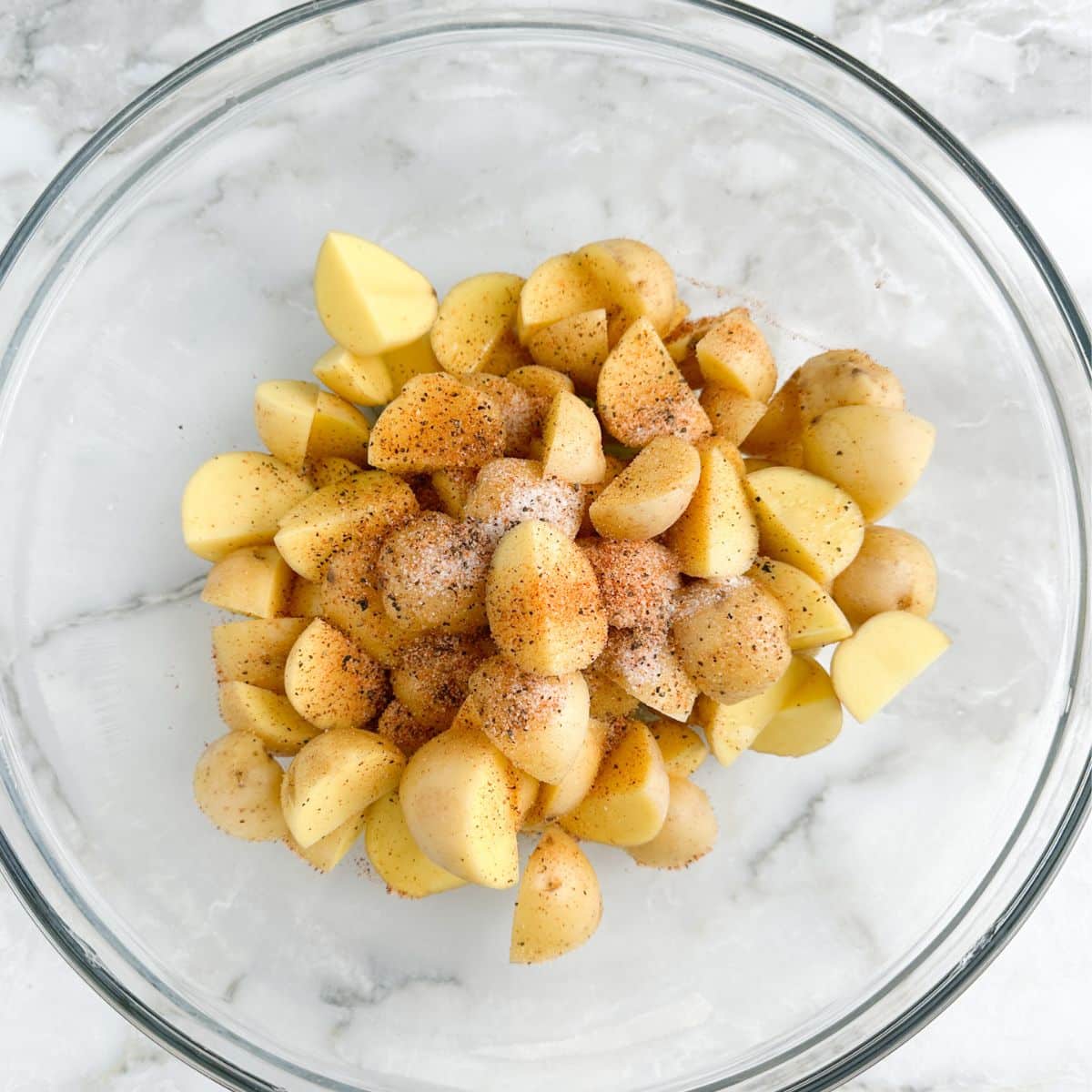 Bowl of diced potatoes and seasoning.