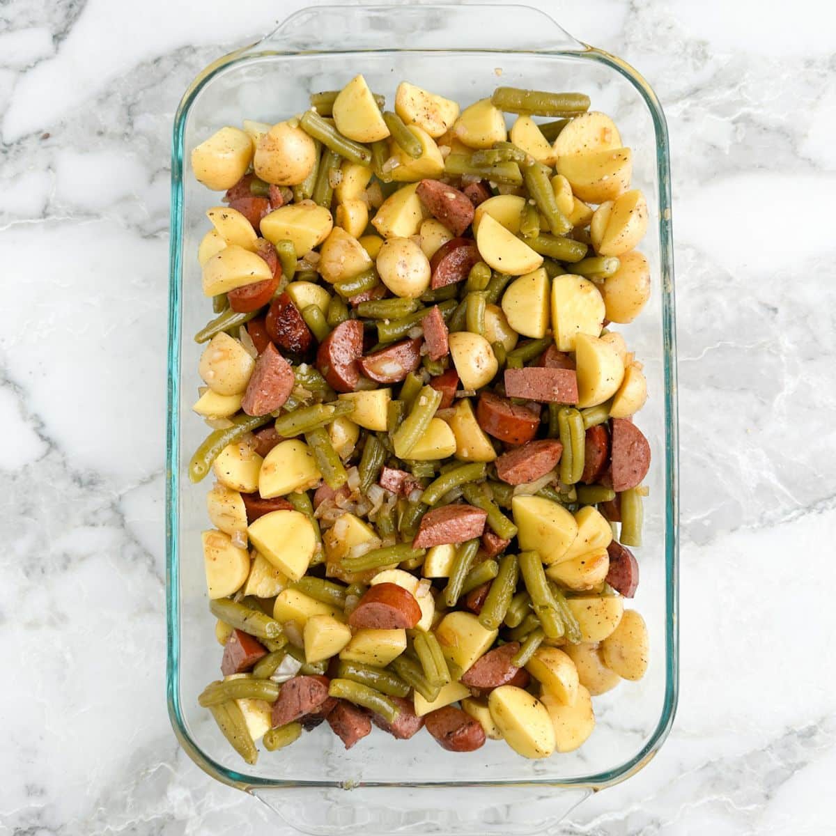 Casserole dish with potatoes, kielbasa, and green beans. 