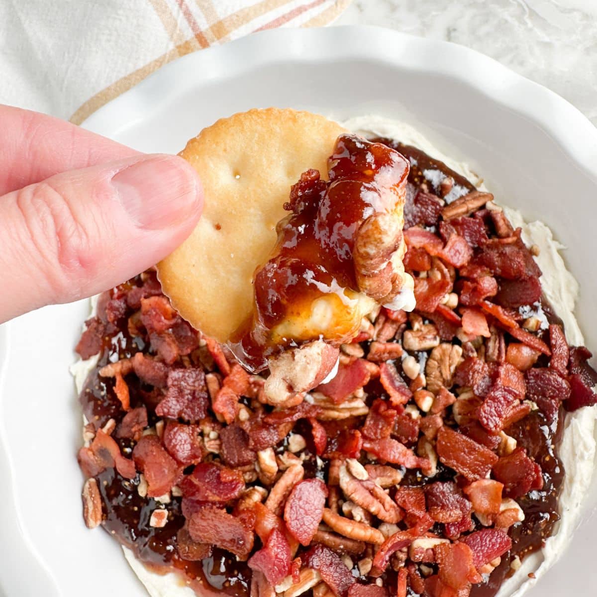 Hand holding cracker with Boursin dip. 