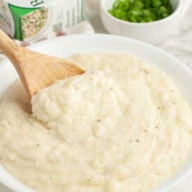 Bowl of mashed potatoes with a wooden spoon.