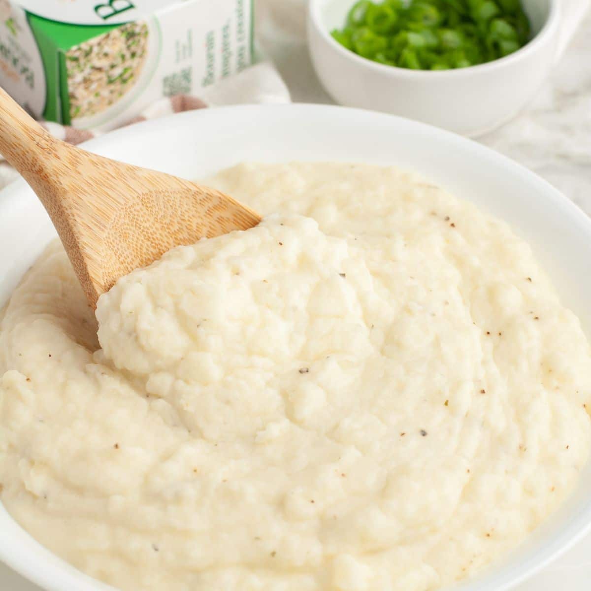 Bowl of mashed potatoes with a wooden spoon.
