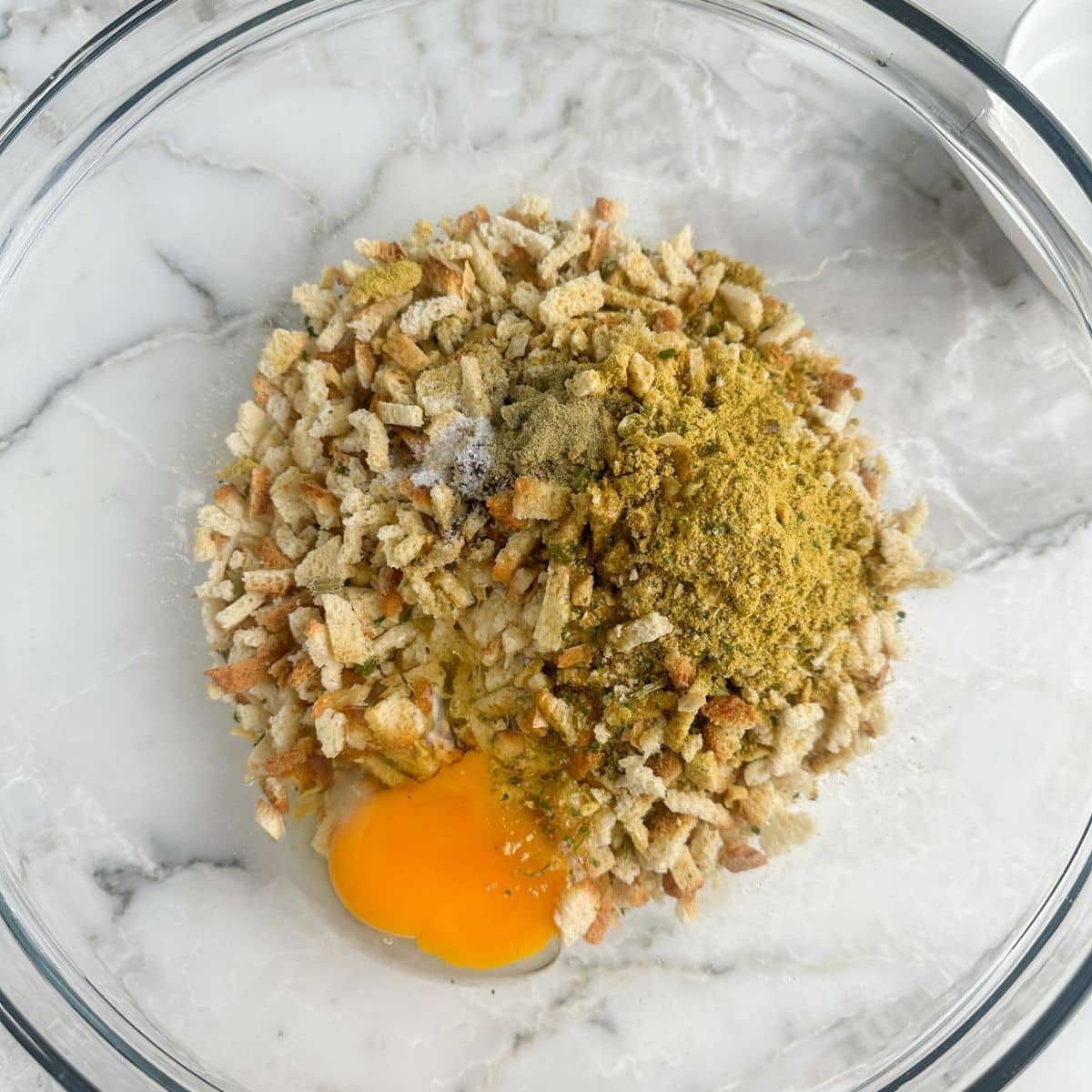 Bowl of stuffing mix with seasonings, and an egg. 