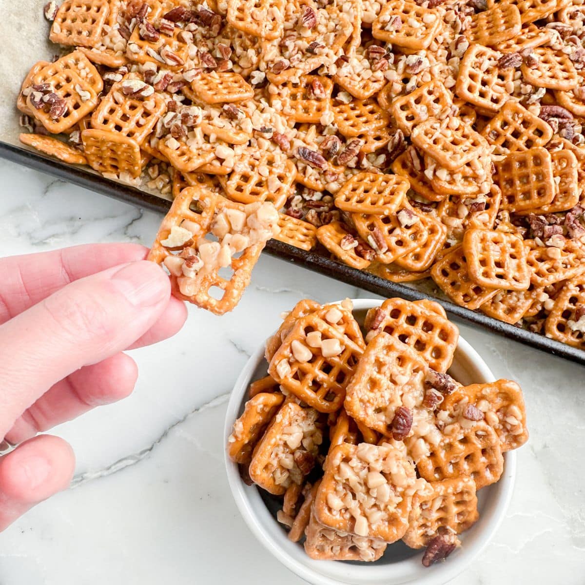 Hand holding a pretzel with toffee.