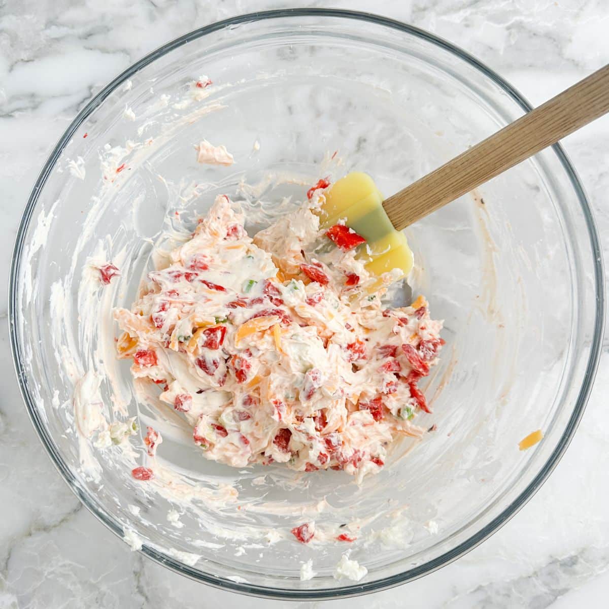 Bowl of roasted red pepper dip with a spatula. 