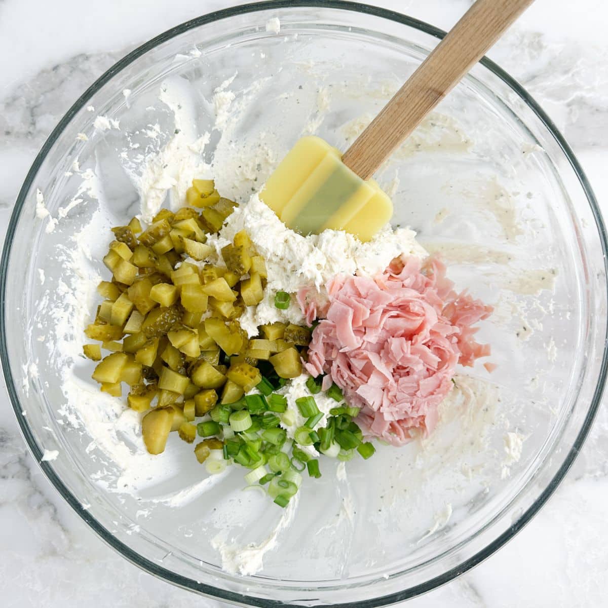 Bowl with cream cheese, chopped dill pickles, ham, and green onions. 