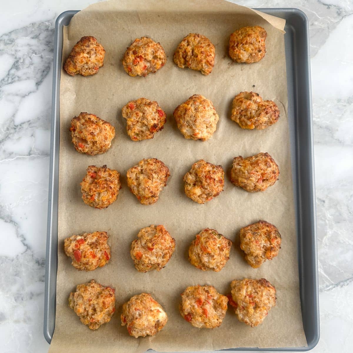 Baking sheet with cooked sausage balls. 