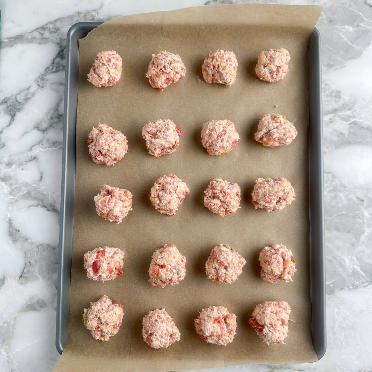 Uncooked sausage balls on a baking sheet. 