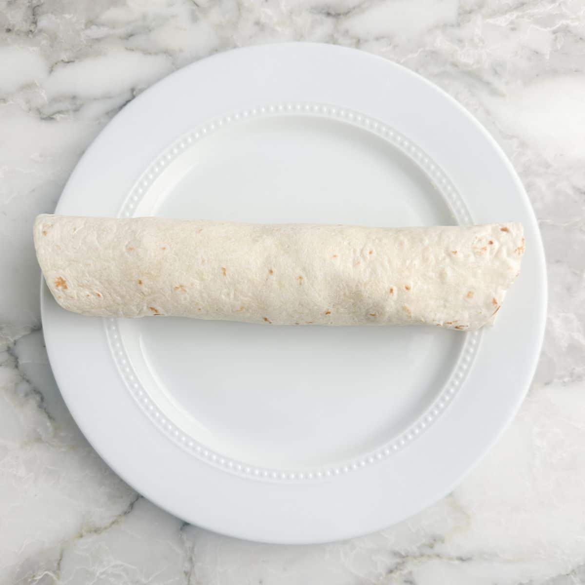 Plate with a rolled up tortilla.