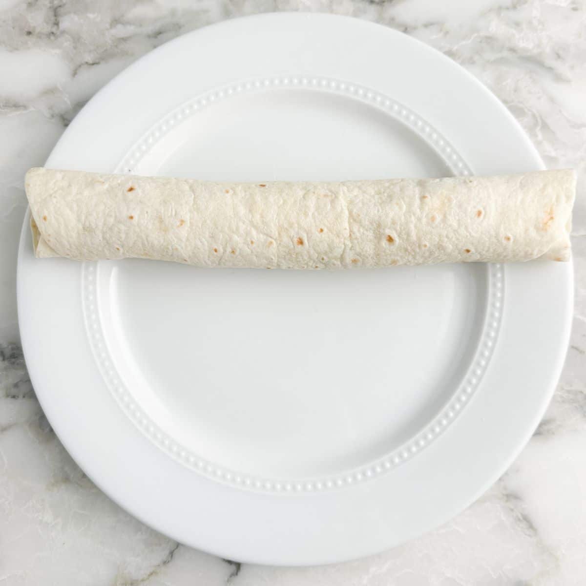 Rolled up tortilla on a plate.