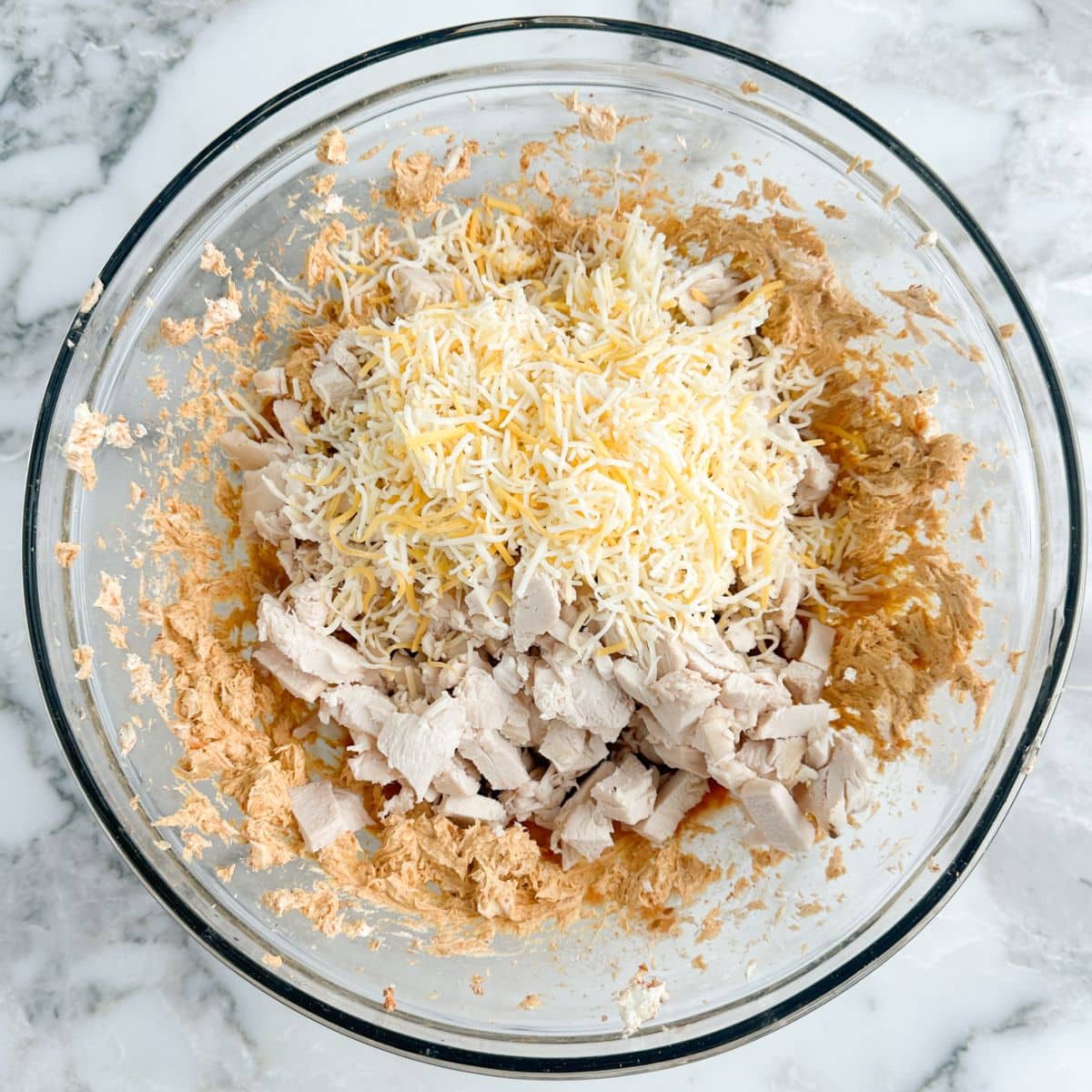 Bowl with cream cheese, chicken, and cheese. 