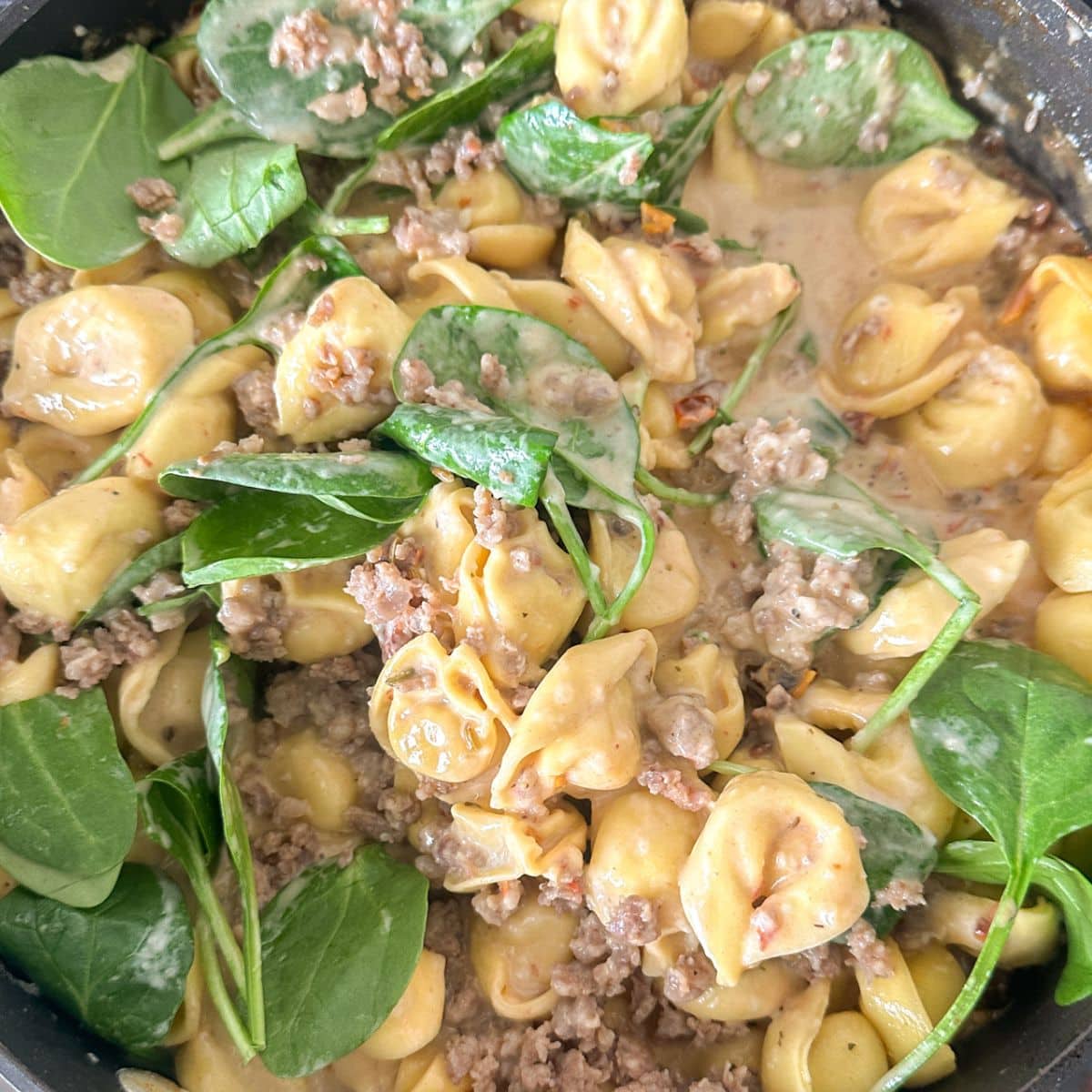 Skillet with tortellini, sausage, and spinach.