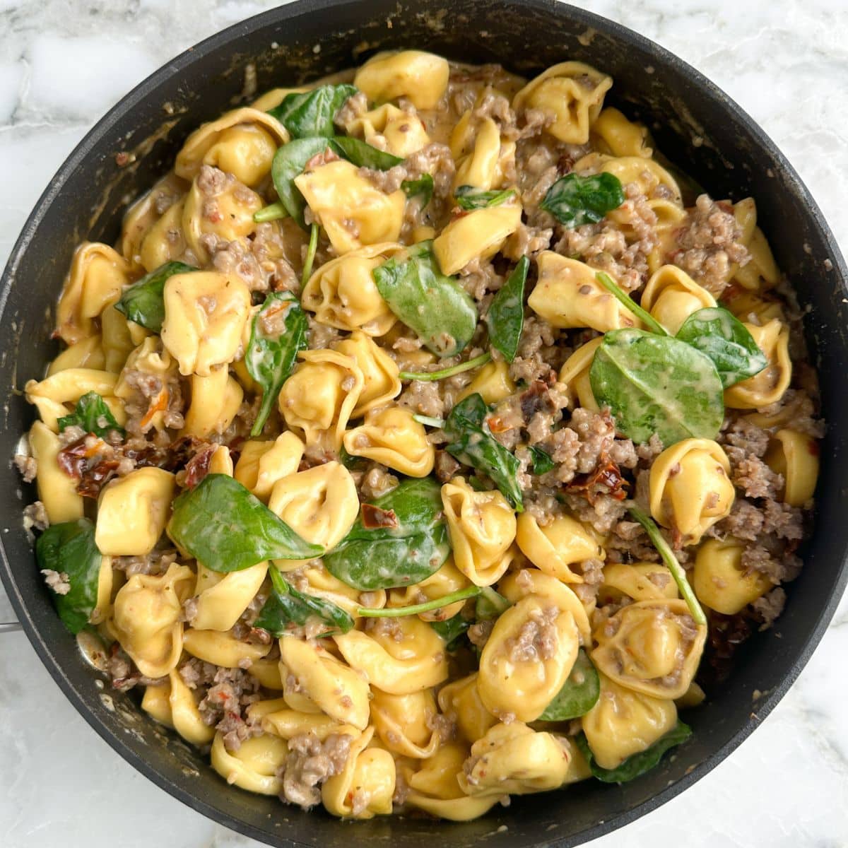 Skillet with tortellini, sausage, and spinach.