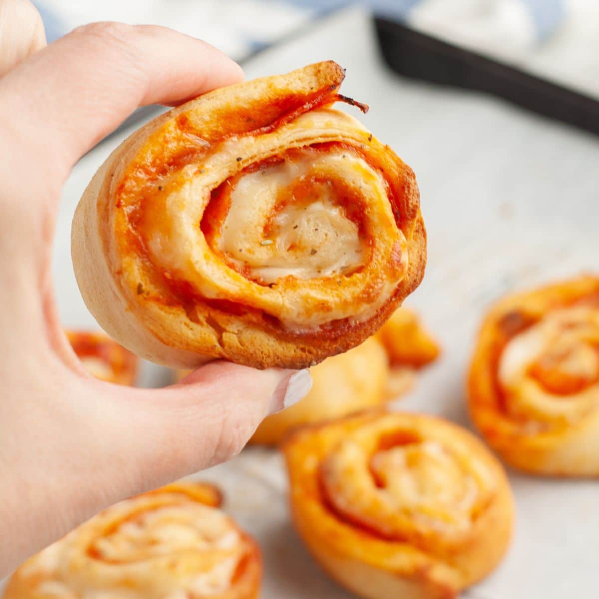 Hand holding a pepperoni pinwheel. 