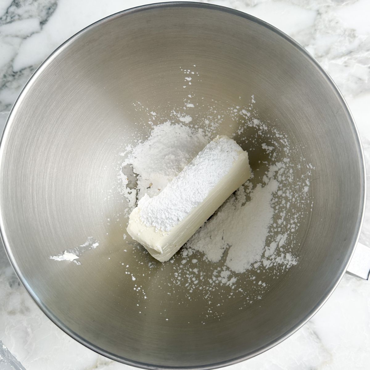 Bowl with cream cheese and powdered sugar.