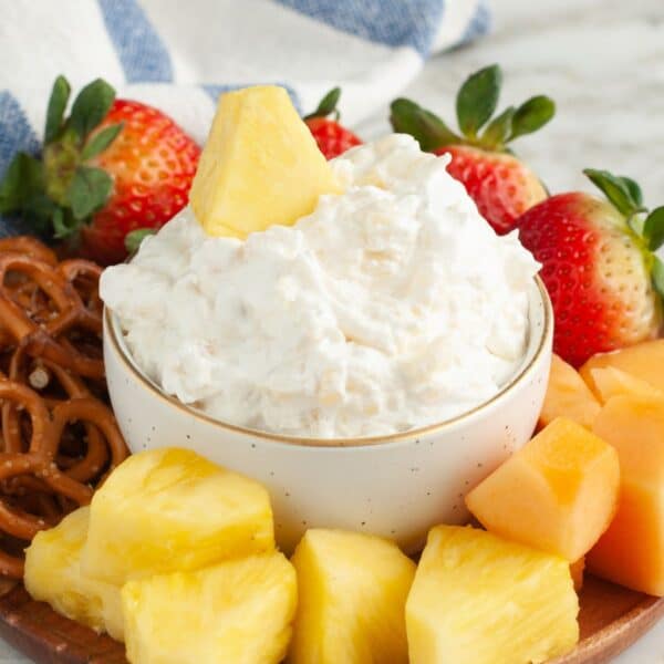 Bowl of pineapple dip surrounded by fruit.