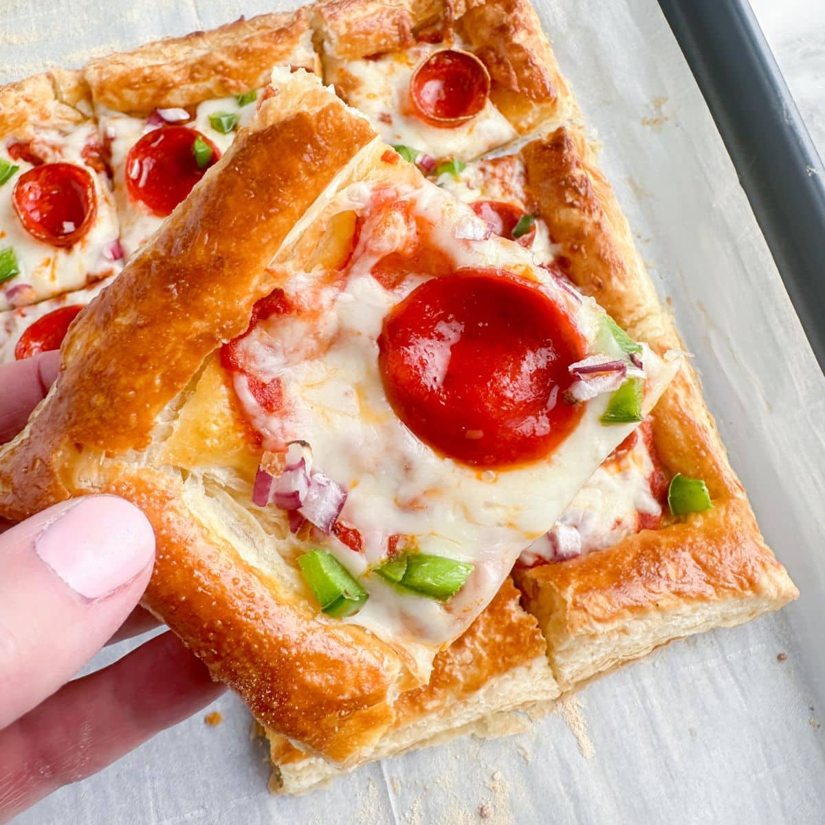 Hand holding a piece of pizza.