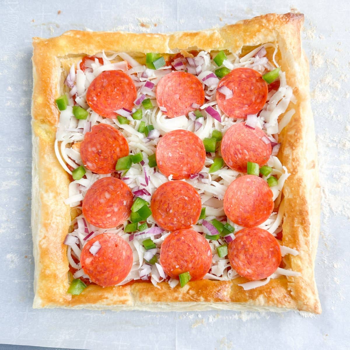 Puff pastry pizza on parchment paper.