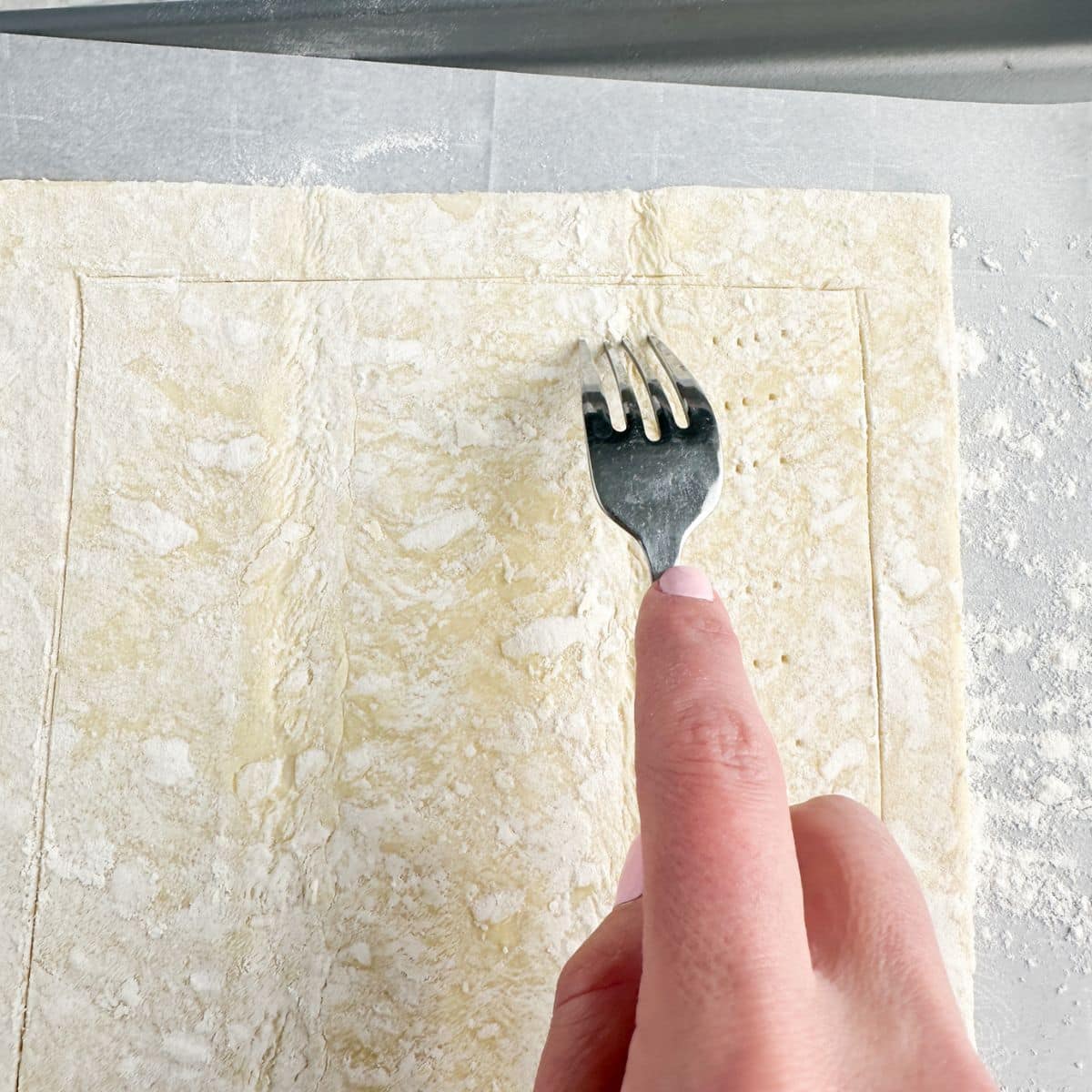 Fork going into puff pastry dough.